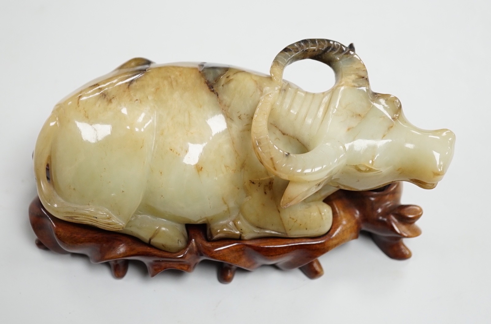 A large Chinese grey and black jade figure of a recumbent buffalo, 17cm long, wood stand